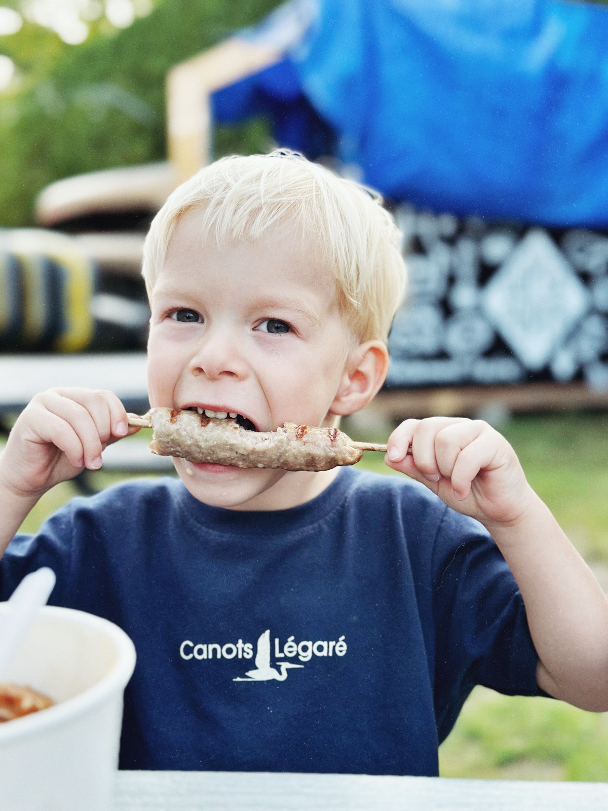 Enfant mangeant une brochette Super-Super chez Canots Légaré