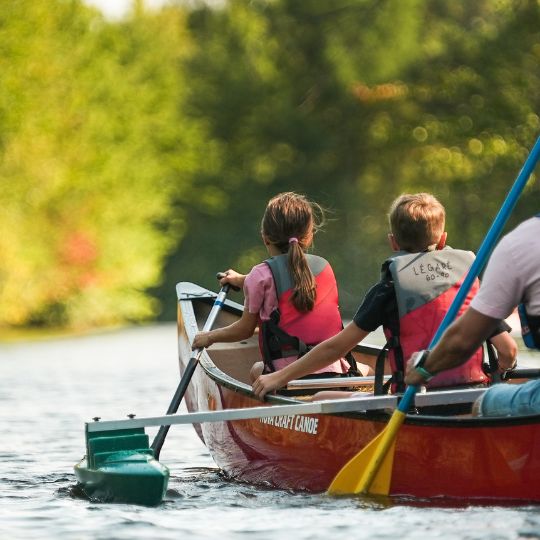 Canots avec trois bancs ou sont assis un adulte et deux enfants