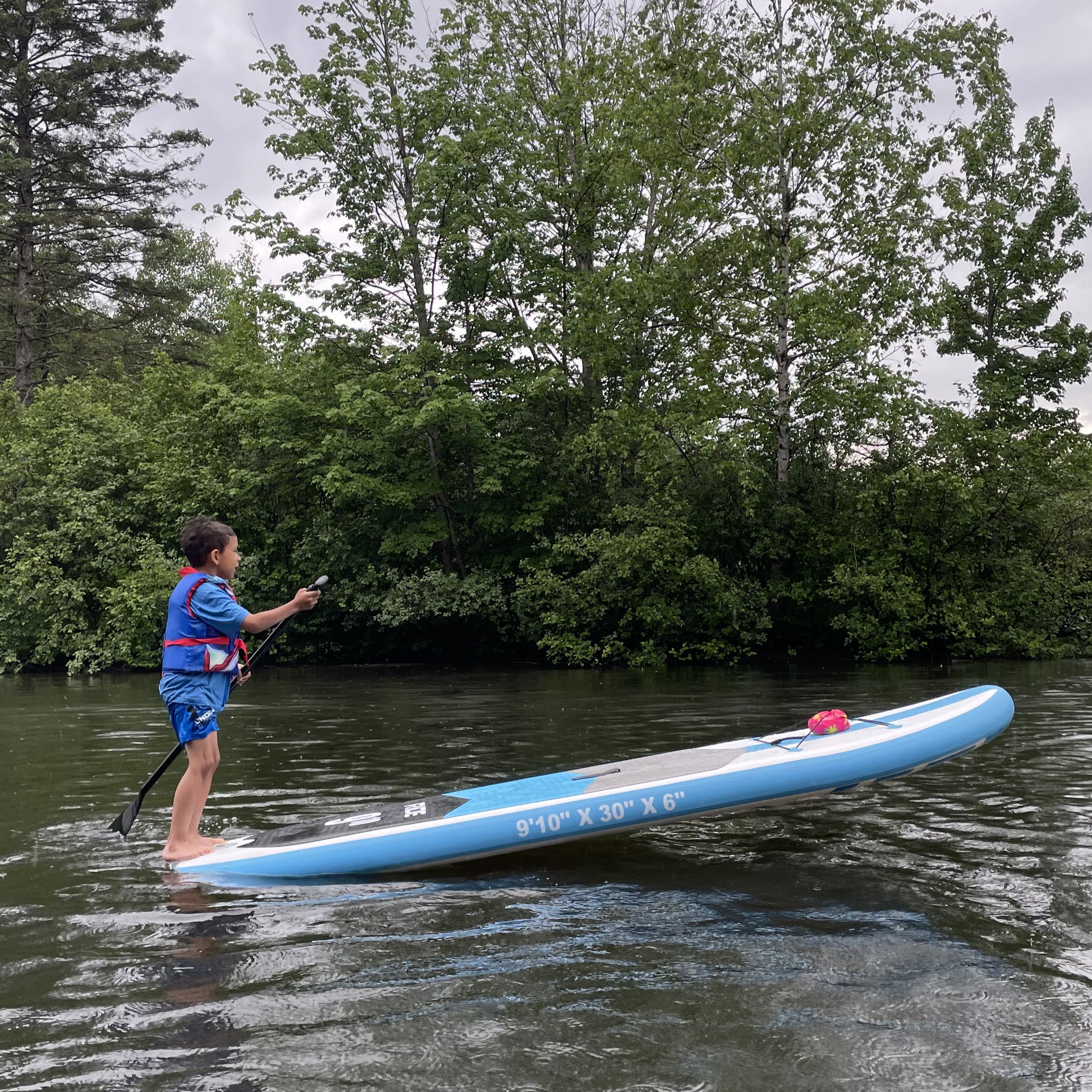 Enfant qui surf sur une planche à pagaie
